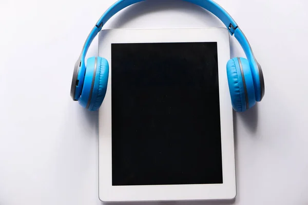Концепция аудио книги. Наушники и цифровой планшет на столе — стоковое фото