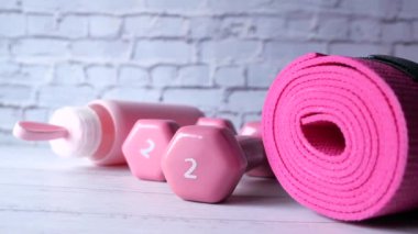  Pembe halterler, spor paspası ve beyaz arka planda su şişesi. 