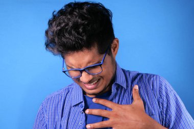 Genç adam kalp ağrısı çekiyor ve göğsünü eliyle tutuyor. 