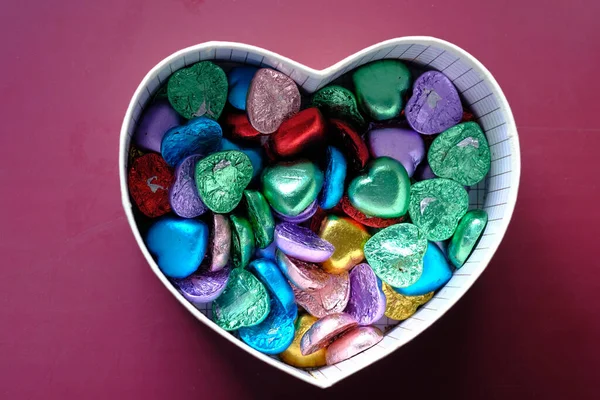 Small heart shape gift with candy on red background — Stock Photo, Image