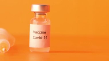 Turuncu arka planda koronavirüs aşısı ve şırıngayı kapatın.