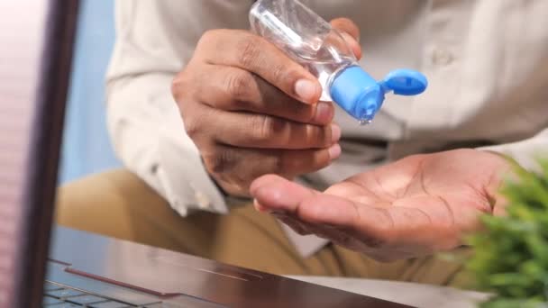 Jovem sentado na mesa offie usando gel desinfetante para prevenir o vírus — Vídeo de Stock
