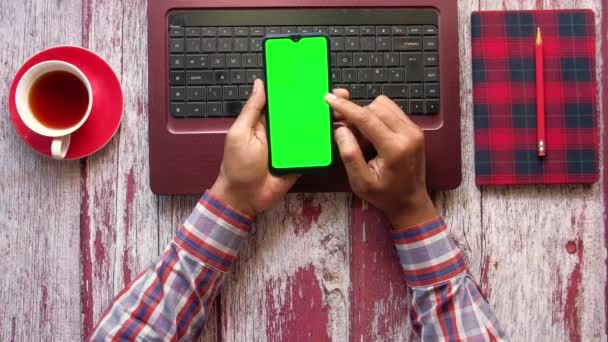 Вид сверху на человеческую руку с помощью смартфона и ввода на ноутбуке — стоковое видео