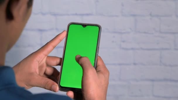 Rückansicht eines Mannes mit Smartphone und grünem Bildschirm — Stockvideo