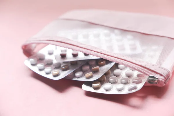 birth control pills on pink background, close up