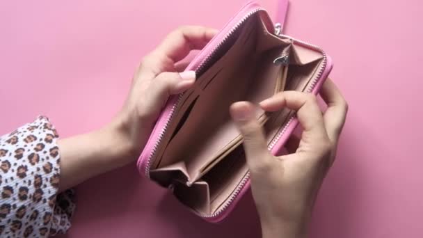 Γυναίκες χέρι ανοίξει ένα άδειο πορτοφόλι σε ροζ φόντο — Αρχείο Βίντεο