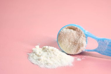 Bebek sütü tozunu ve pembe arka plandaki kaşığı kapat..