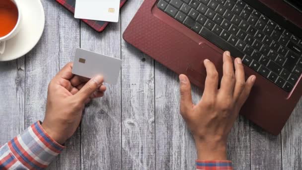 Adamın elleri kredi kartını tutuyor ve internetten bilgisayar alışverişi yapıyor. — Stok video