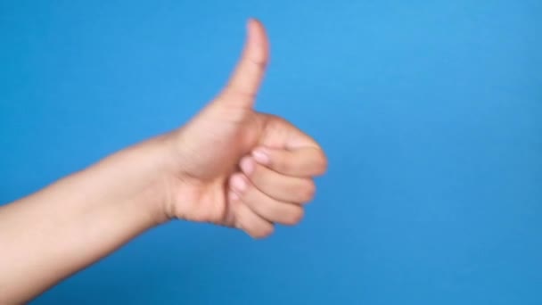 Vrouwen hand tonen een duim-up op blauwe achtergrond — Stockvideo