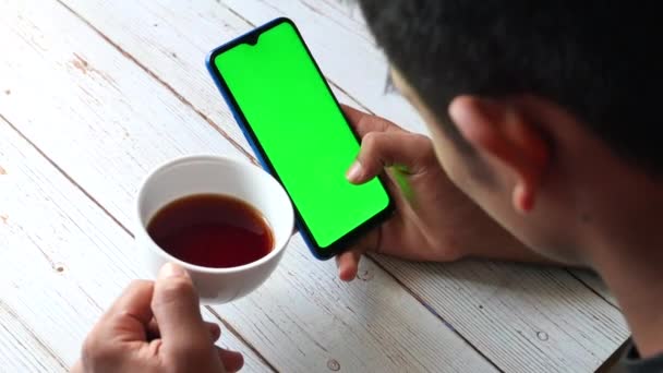 Top pohled na muže ruka drží chytrý telefon a pití čaje — Stock video