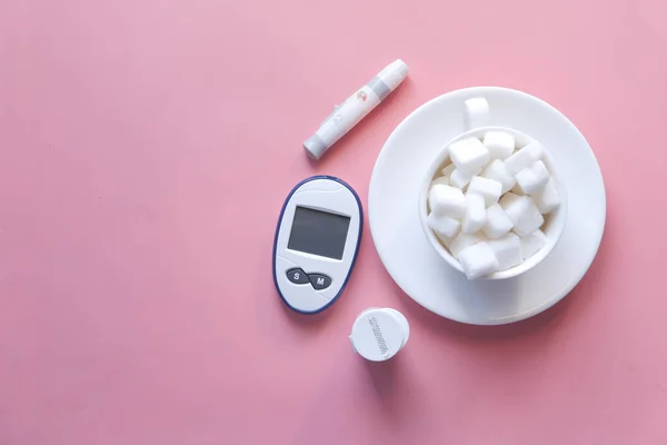 Diabetiska mätverktyg och socker kub ob rosa bakgrund — Stockfoto