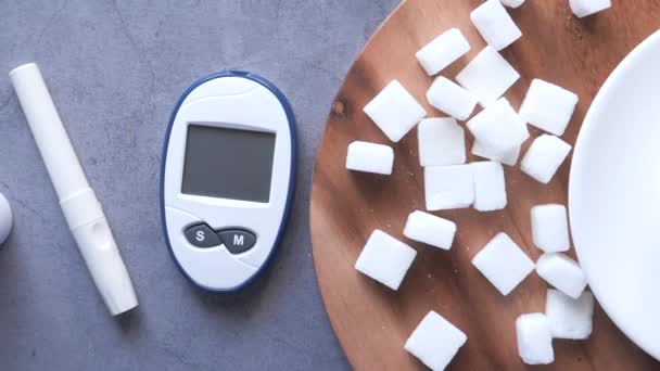Diabetikermessgeräte und Zuckerwürfel vor schwarzem Hintergrund — Stockvideo