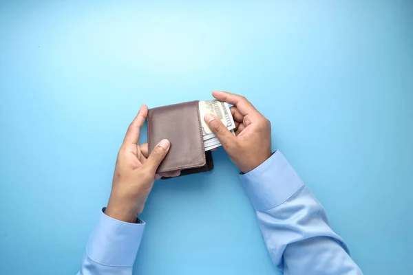 man hand taking cash out from wallet on blue background