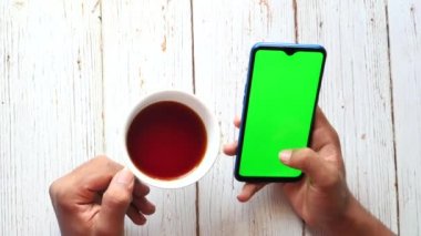 Akıllı telefon kullanan ve kahve içen bir adamın üst görüntüsü. 