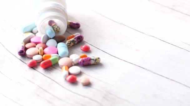 Close-up van kleurrijke pillen morsen op witte achtergrond — Stockvideo