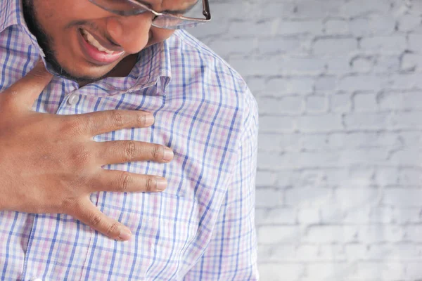 Jonge man lijden pijn in het hart en houden borst met de hand — Stockfoto