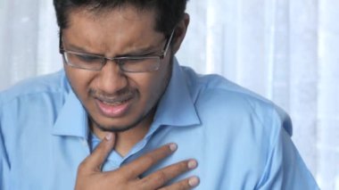 Kanepeye oturup öksüren olgun hasta bir adam. 