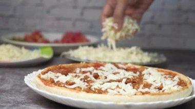 Kadınlar pizzaya mozzarella peyniri ekler.