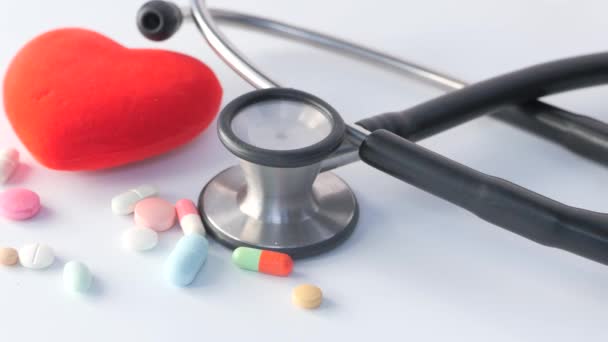 Close up of stethoscope, pills and heart shape on white background — Stock Video