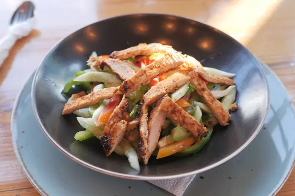 Жареная курица и свежий овощной салат на столе. — стоковое фото