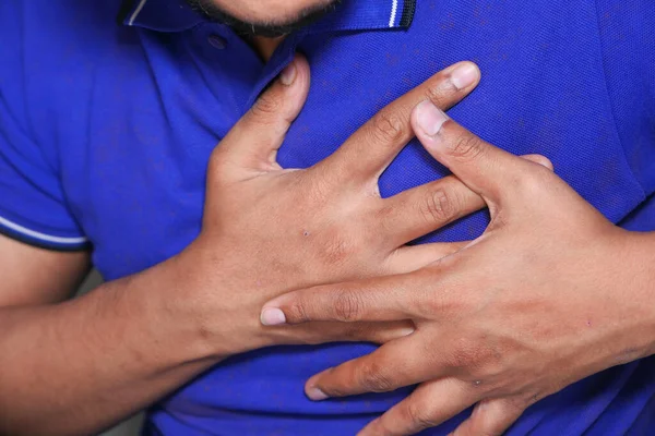 Jonge man lijden pijn in het hart en houden borst met de hand — Stockfoto