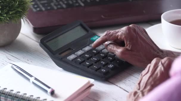 Tangan wanita senior menggunakan kalkulator di atas meja — Stok Video