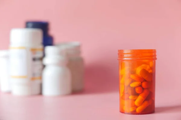 Närbild av piller och kapsel behållare på rosa bakgrund — Stockfoto