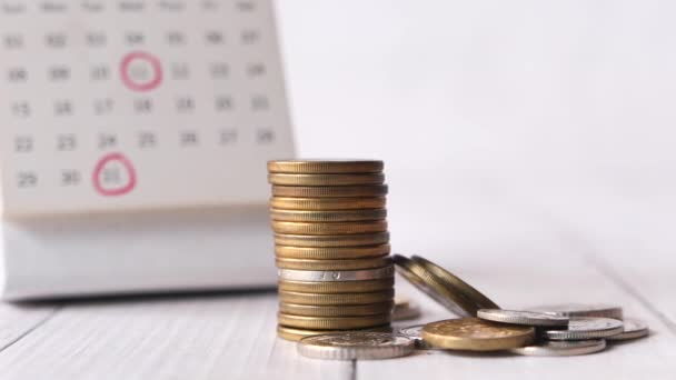 Stack of coins and calendar on white background — Stock Video