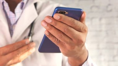Beyaz önlüklü doktor akıllı telefon kullanıyor..