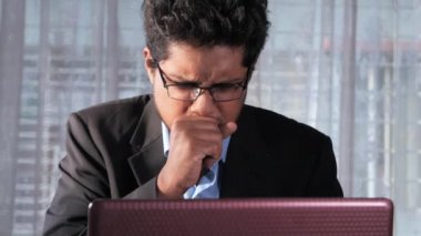  Genç hasta işadamı dizüstü bilgisayarla çalışırken öksürüyor 