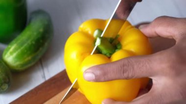doğrama tahtasındaki sarı renkli kapsicum kesiliyor 