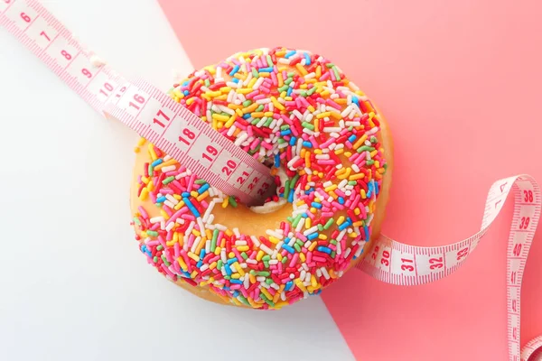 Close up of donuts and measurement tape on pink background. — Stock Photo, Image
