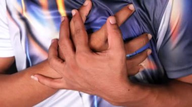 Genç adam kalp ağrısı çekiyor ve göğsünü eliyle tutuyor. 