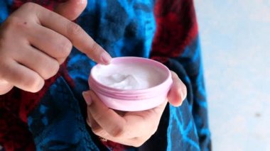 Kadın ev manzarasında cildine güzellik kremi sürüyor. 