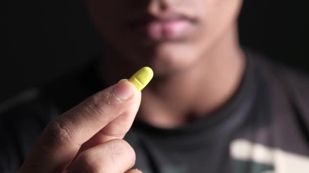 年轻人手拿着用黑色隔离的药丸 — 图库视频影像