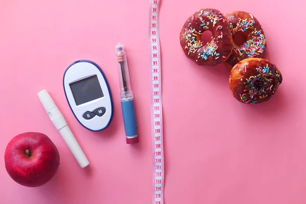 Ferramentas de medição diabéticos, insulina e donuts em rosa — Fotografia de Stock