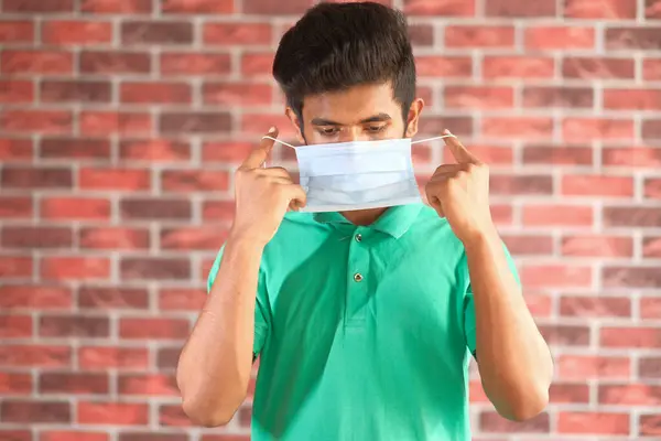 Jong aziatische man zetten chirurgische gezicht masker indoor — Stockfoto