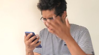 üzgün genç adam akıllı telefondan haber okuyor. 