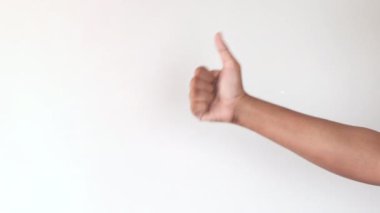 Adam eli beyaz duvarda baş parmağını gösteriyor. 