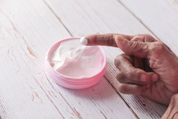 Mujer mayor aplicando crema de belleza sobre la piel — Foto de Stock