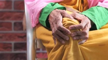 Yaşlı kadınlar sandalyede oturup diz eklem ağrısı çekiyorlar.