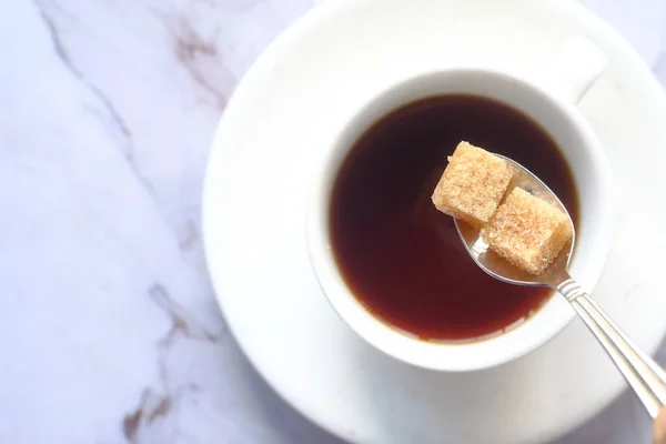 Xícara de chá e cubo de açúcar mascavo na mesa — Fotografia de Stock