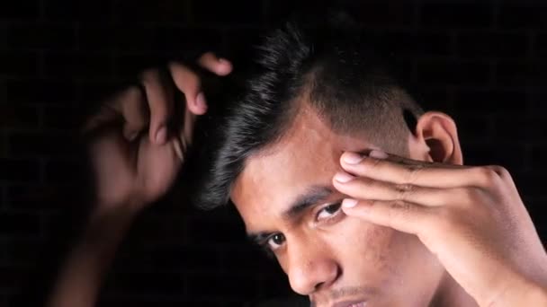 Side view of man styling hair with comb on black background, — Stock Video