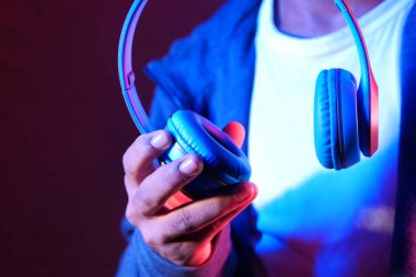 Mavi arka planda kulaklık tutan bir adam. 