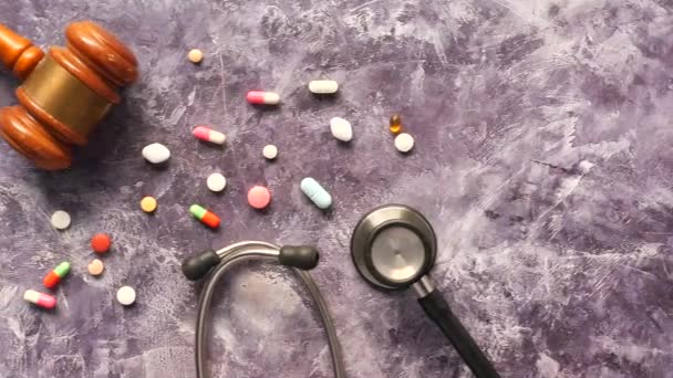 Top view of gavel, stethoscope and pills on black background — Stock Video