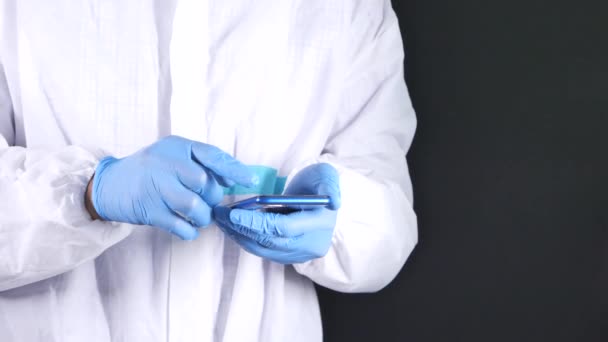 Dokter tangan dalam sarung tangan pelindung menggunakan smartphone. — Stok Video