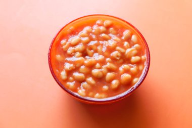 Turuncu arka planda bir kasede lezzetli fasulyeler. ,