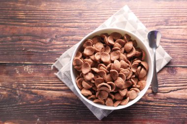  Tahta arka planda bir kasede çikolatalı mısır gevreğinin üst görüntüsü. 