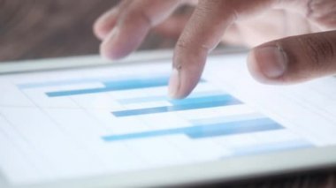 Erkekler çubuk grafiğini ve dijital tableti elle analiz ederler. 