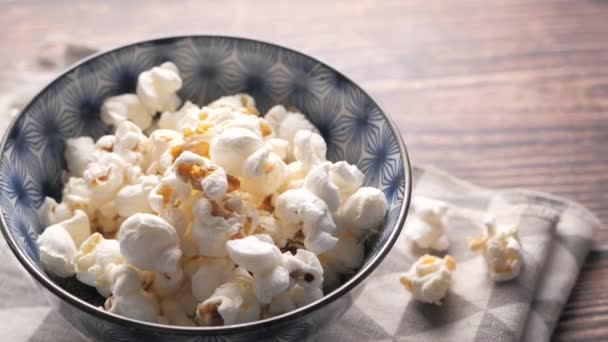 Popcorn in een kom op houten bureau — Stockvideo